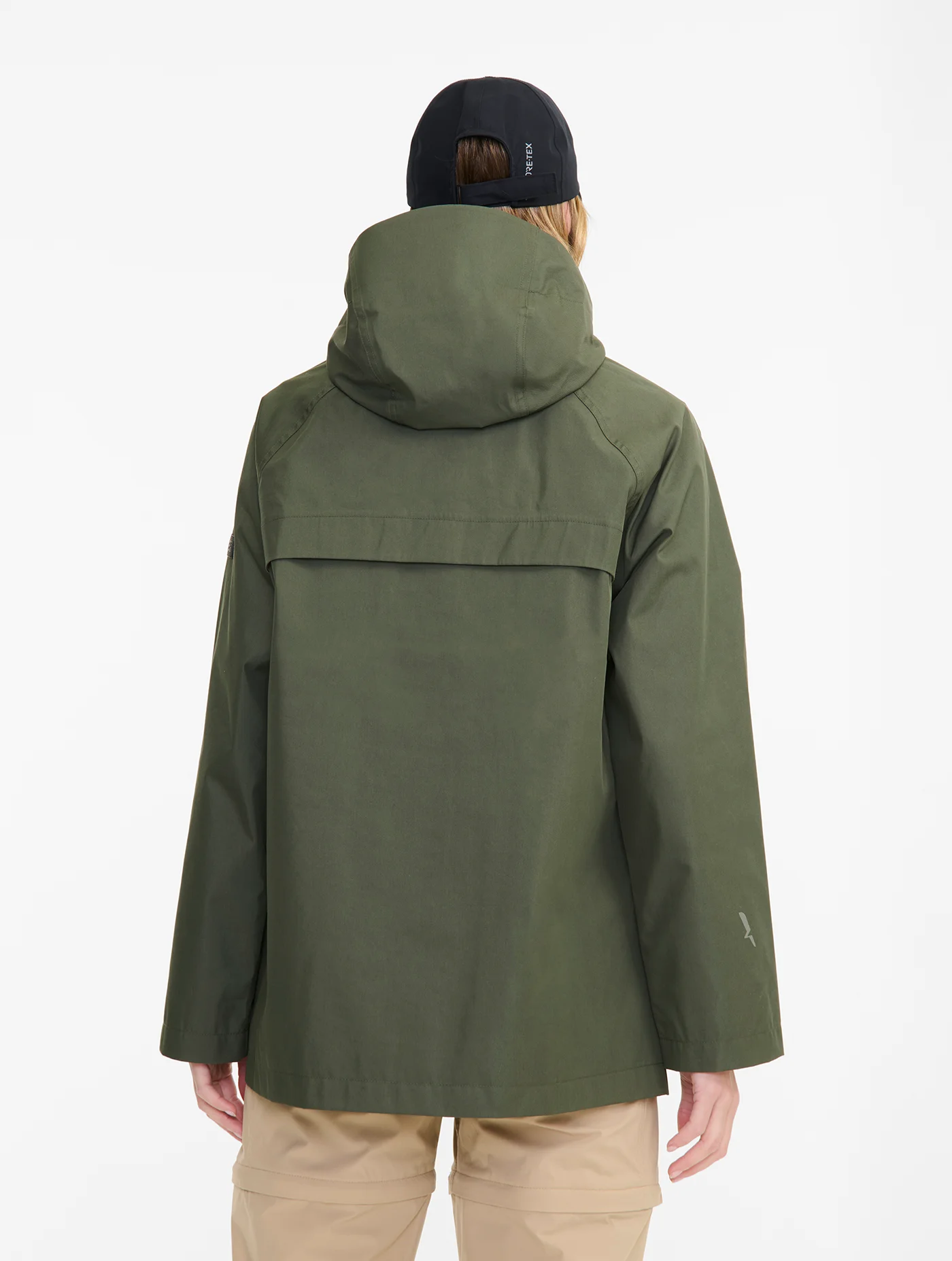 Person wearing an olive green hooded jacket and beige pants, viewed from the back.