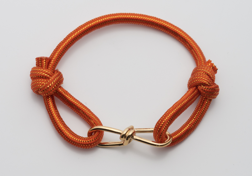 Orange paracord bracelet with gold clasp on a white background.